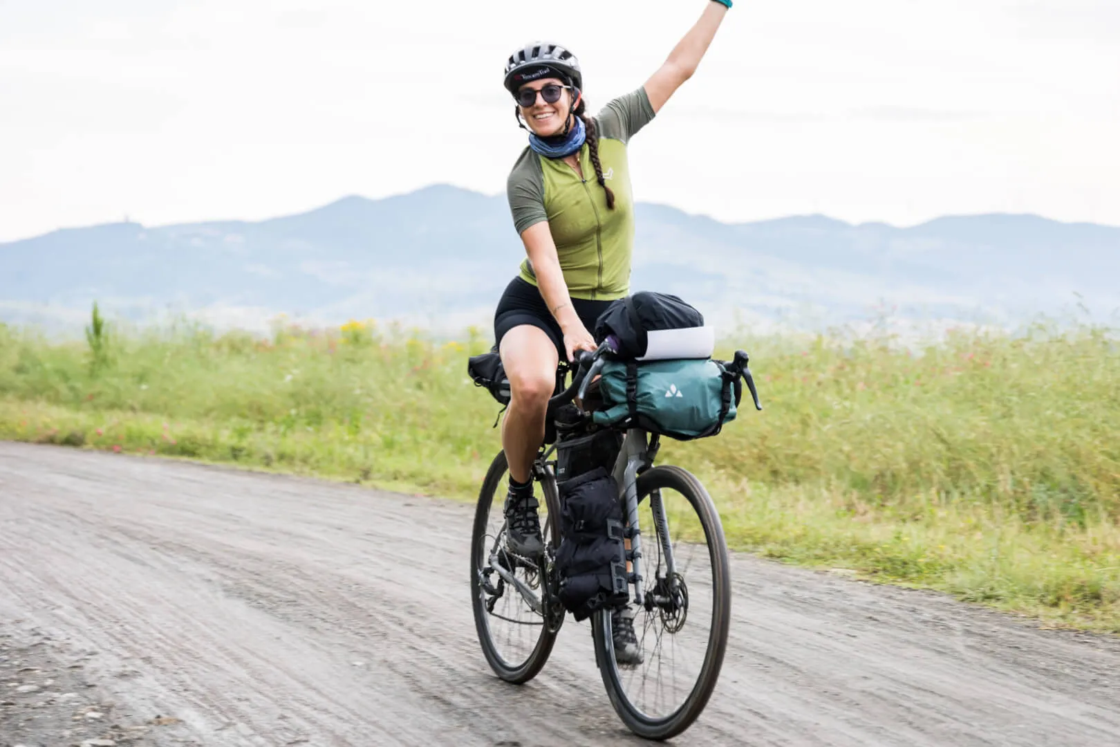 A rider raising her arm on a white road