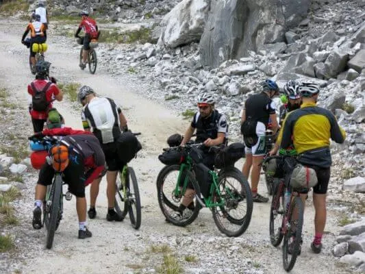 A group of riders with loaded bikes on a forest gravel road
