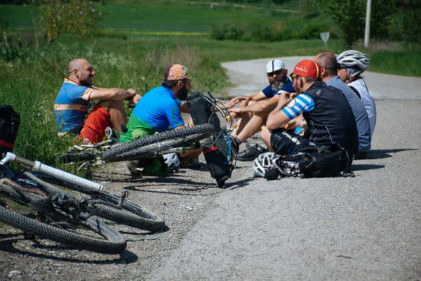 Riders sitting by the road with their bikes on the ground
