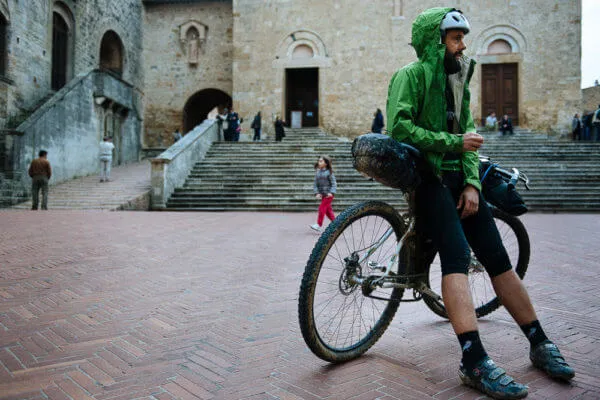 A rider with a loaded bike in a stone square