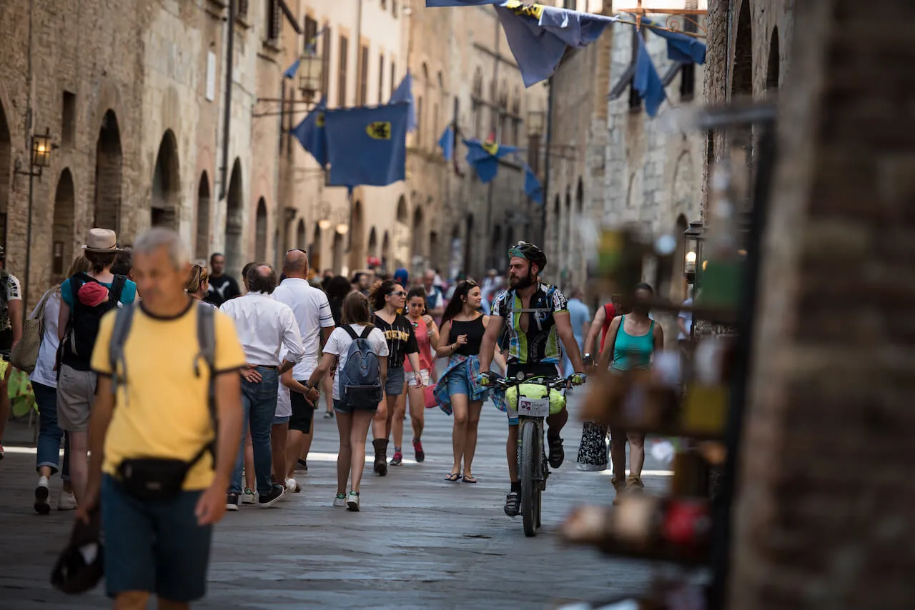 Riders and passers-by in a street of San Gimignano