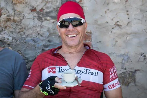 A smiling rider holding an espresso cup