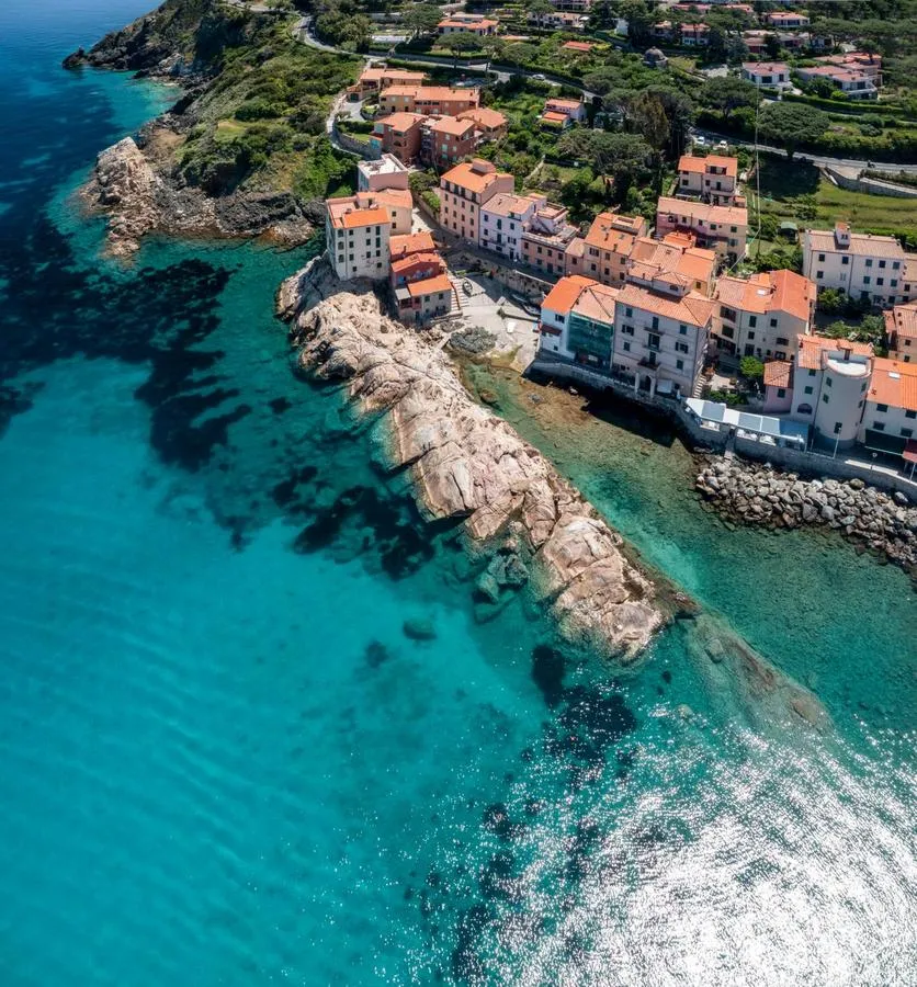 Borgo dell'Isola d'Elba affacciato sul mare, con le case colorate e gli scogli davanti