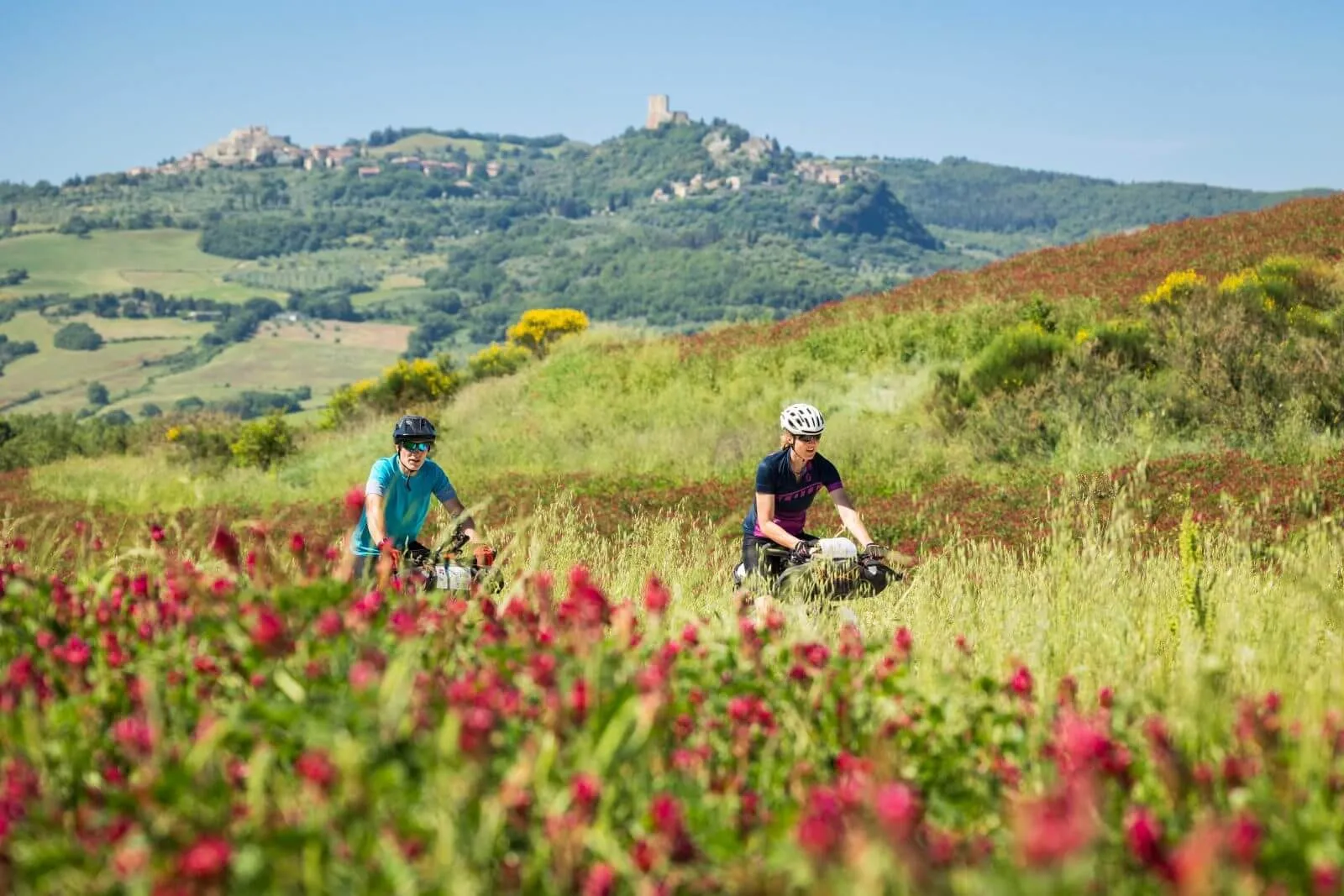 Due rider in un campo di papaveri, con un borgo sulla collina