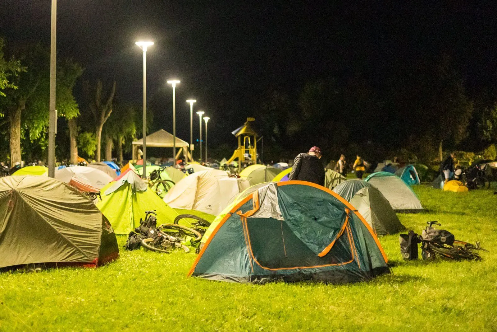 Un Base Camp di notte, le tende sul prato sotto i lampioni