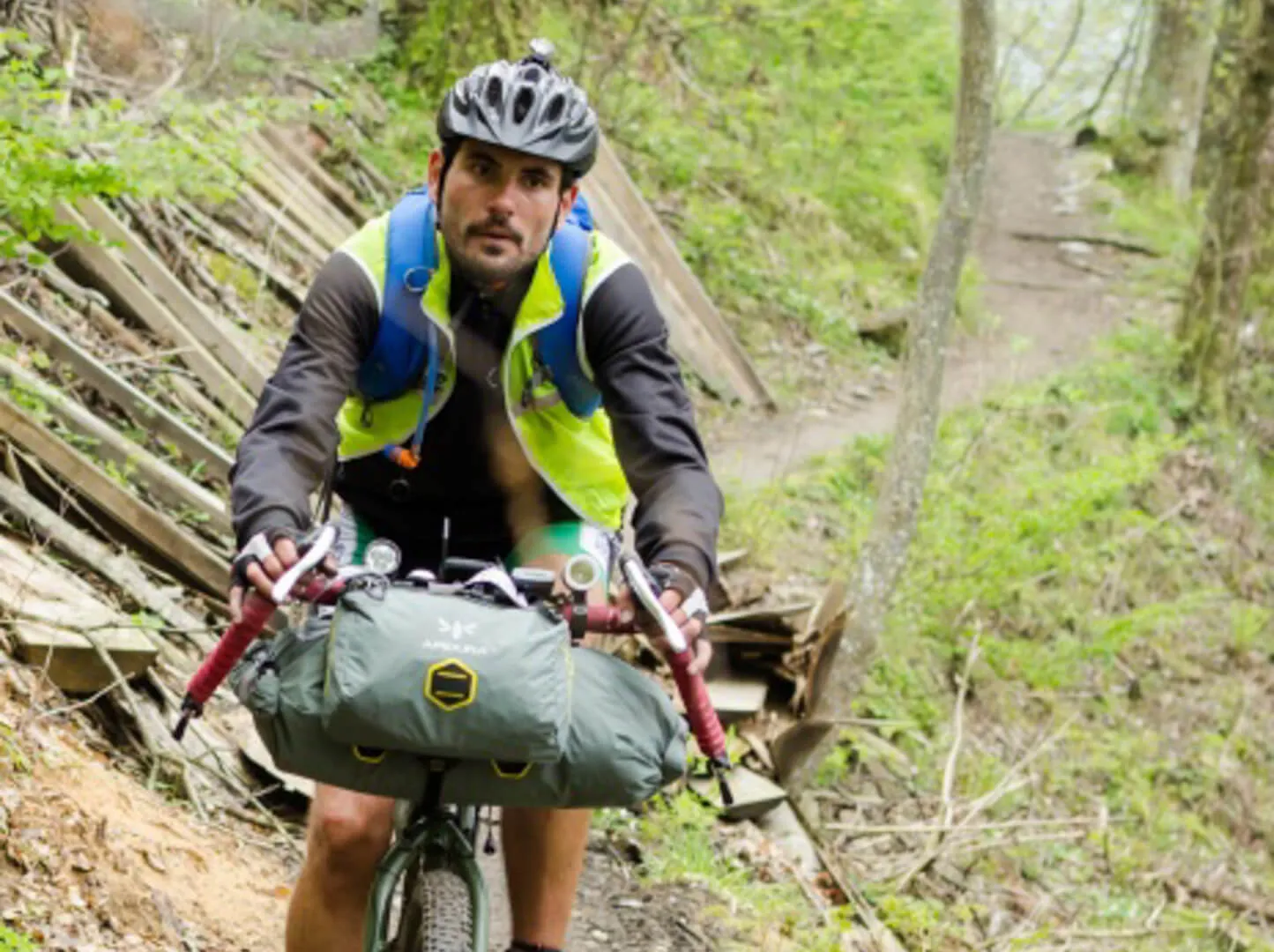 A rider pushing the bike up a forest trail