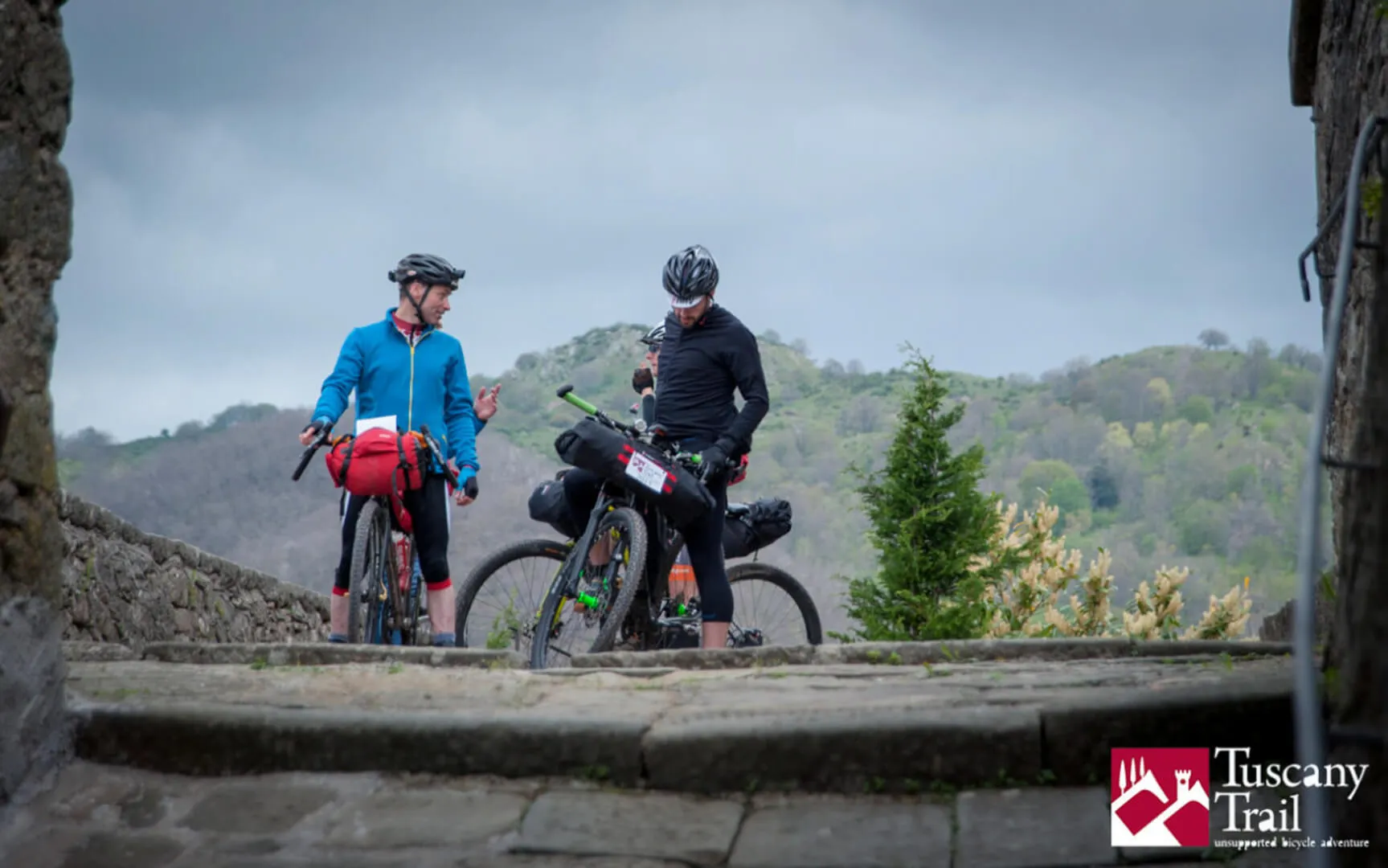 Two riders on a stone wall overlooking the hills