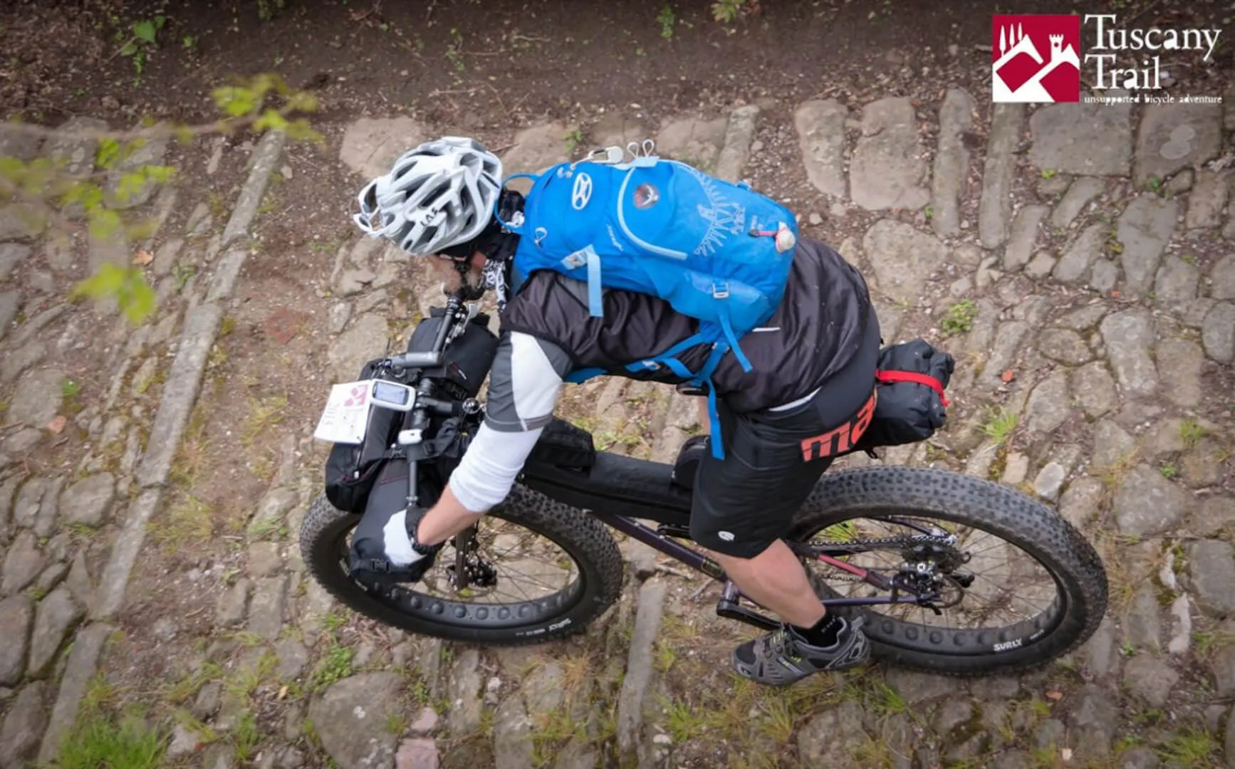 A rider leaning into a turn on a cobbled forest path