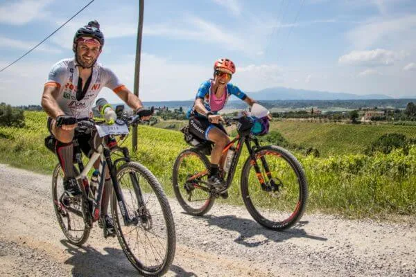 Two smiling riders on a white road