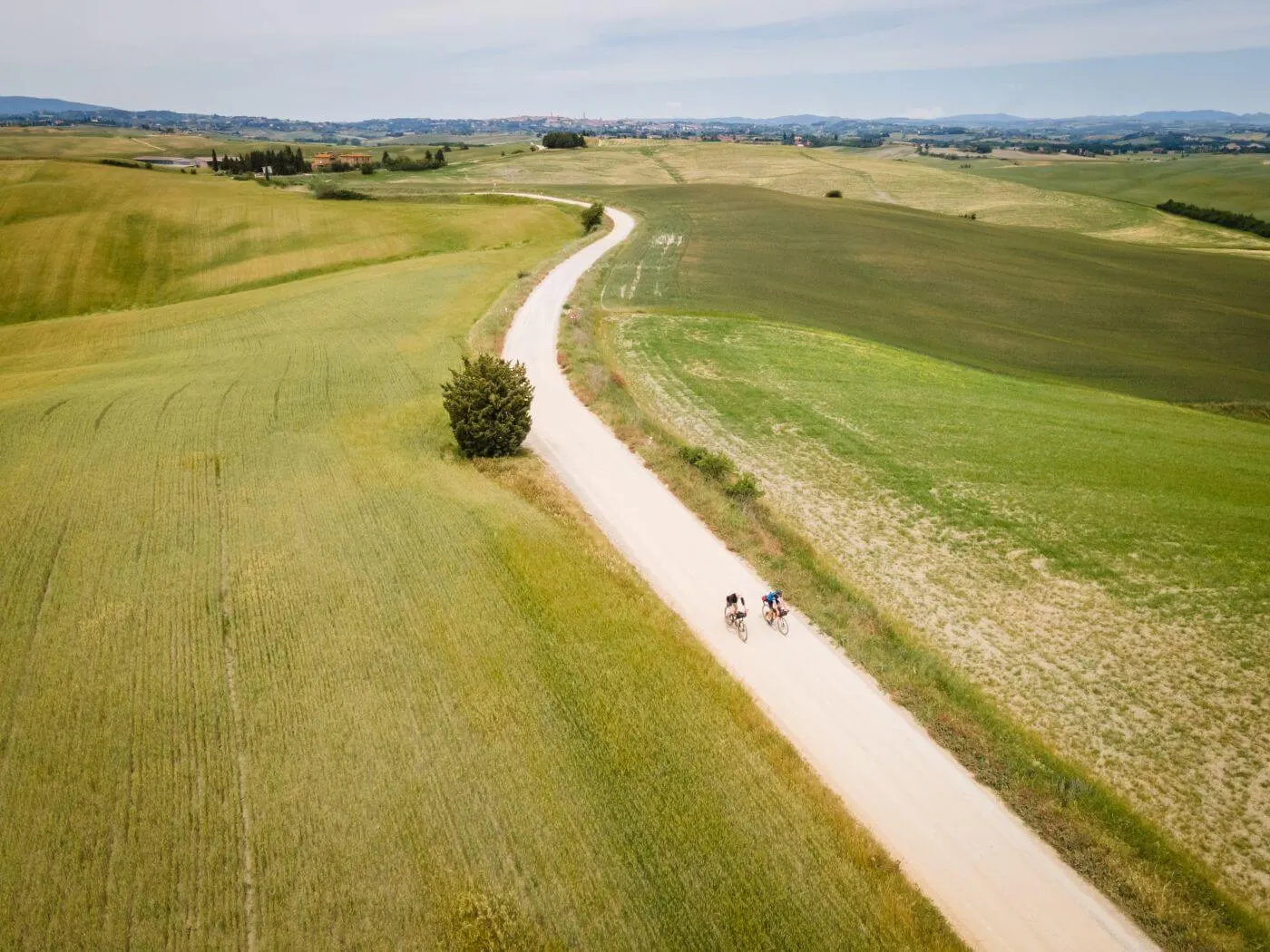 A white road through green hills, seen from above