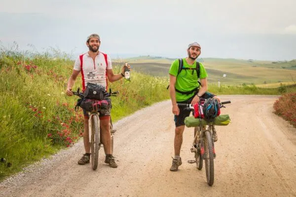 Two riders raising their arms on a white road
