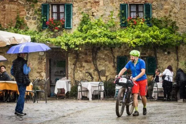 A rider in front of a trattoria, in the rain