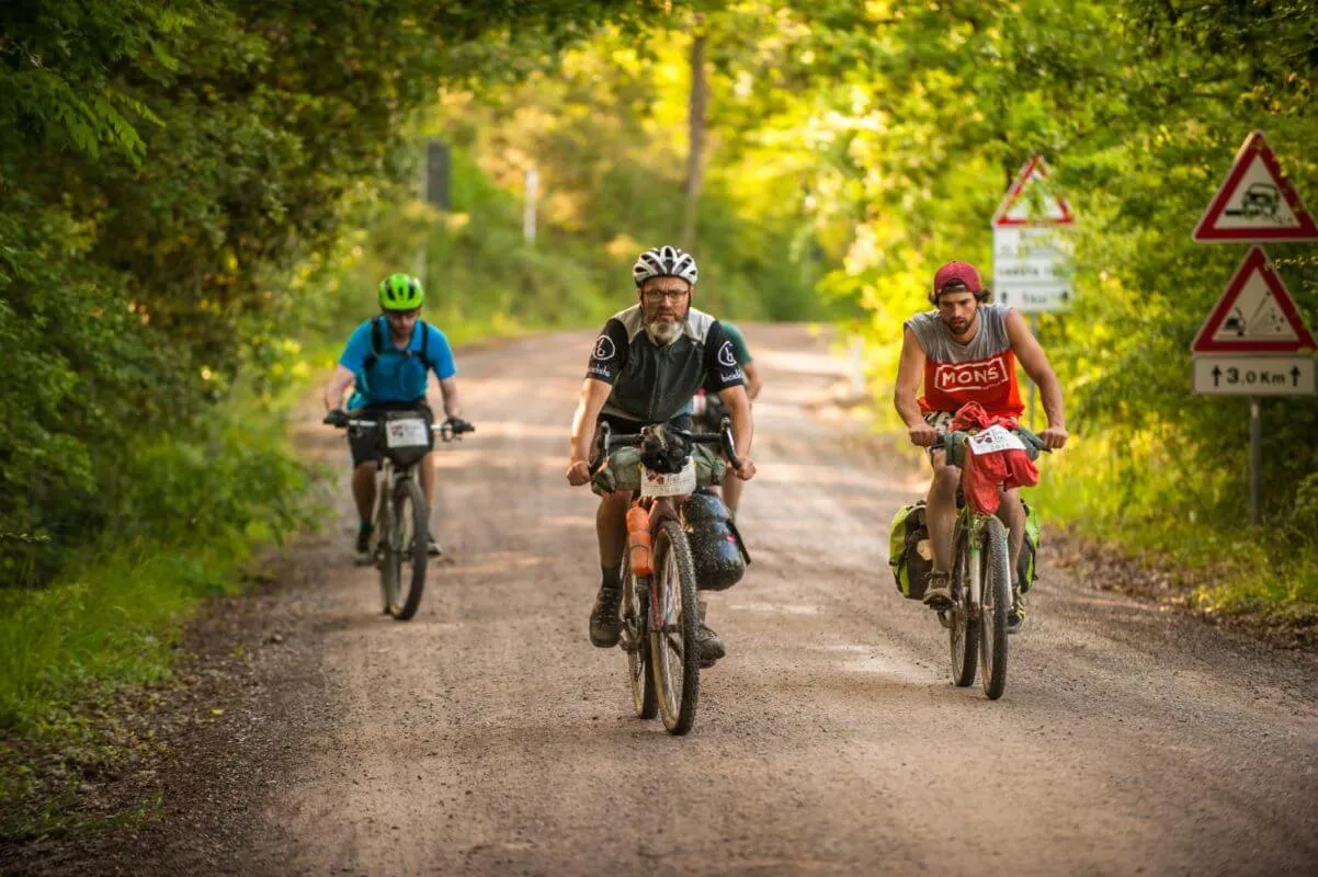 Three riders on a gravel road under the trees